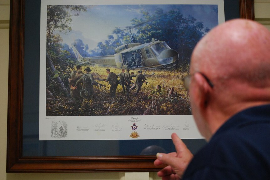 A man looks at a picture of a helicopter in war.