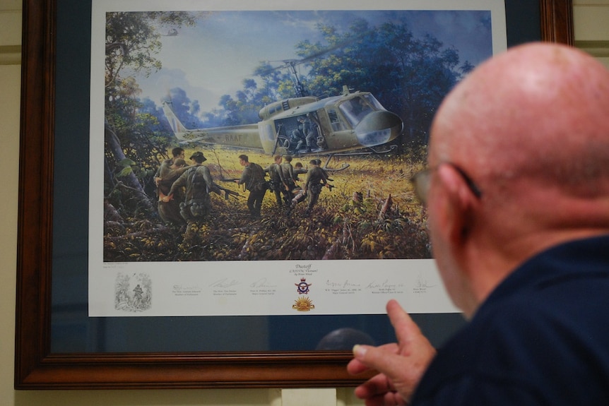 A man looks at a picture of a helicopter in war.