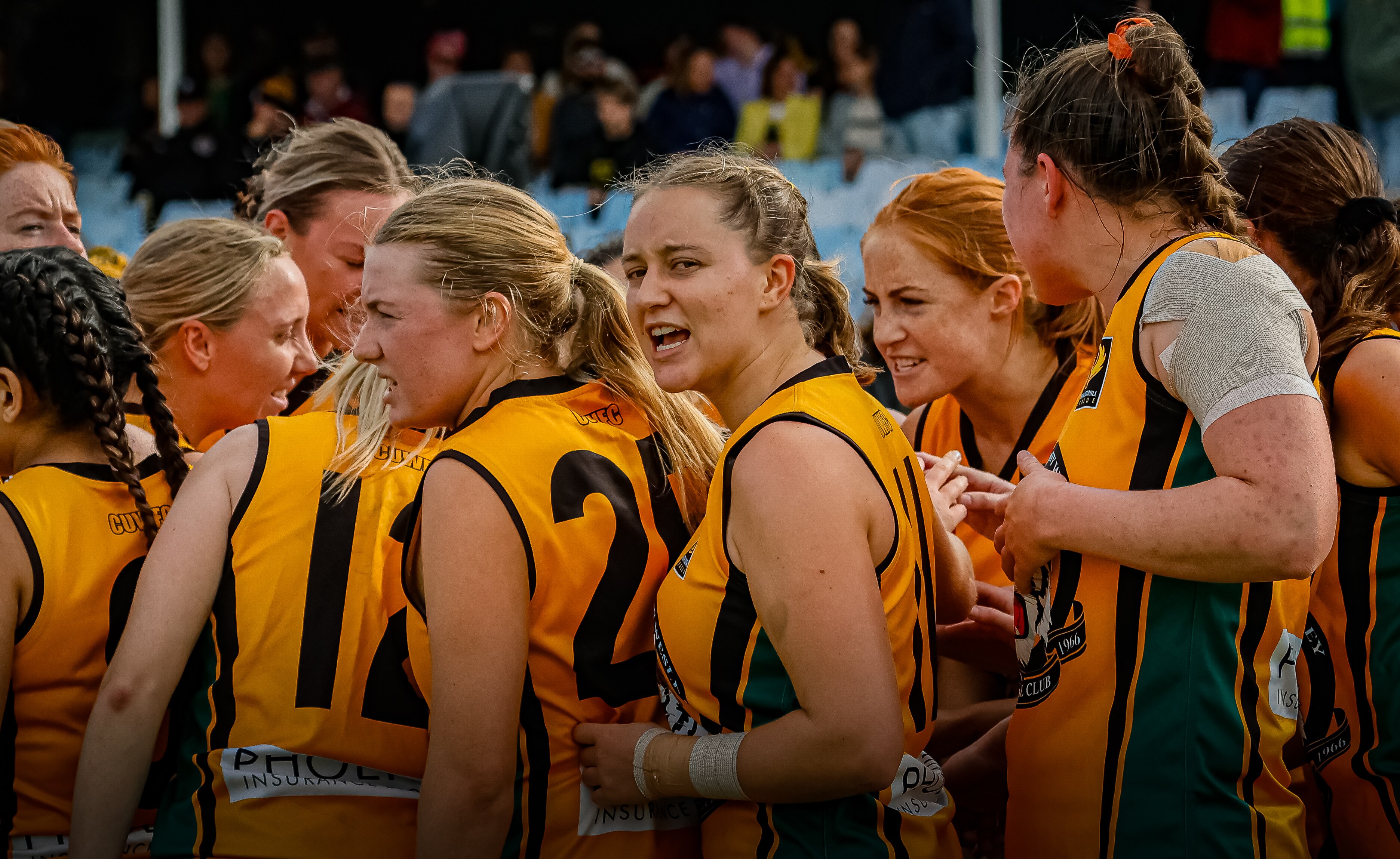 Curtin Uni Wesley players stand arm in arm in a huddle during an Aussie rules match.