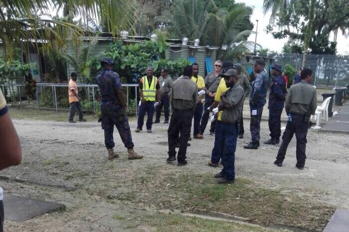 More than a dozen local men stand around at the Manus Island detention centre.