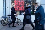 Pedestrians walk past an money exchange displaying very high US Dollar buy and sell rates versus the Rouble.