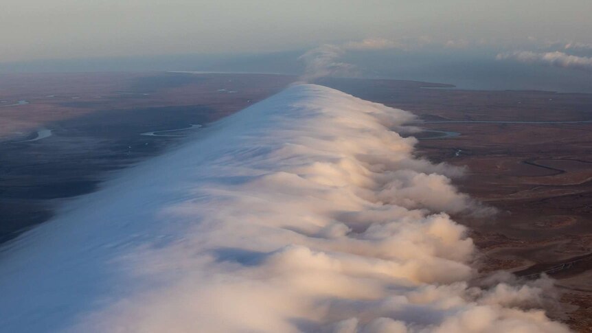 A large white cloud with land and sea below.