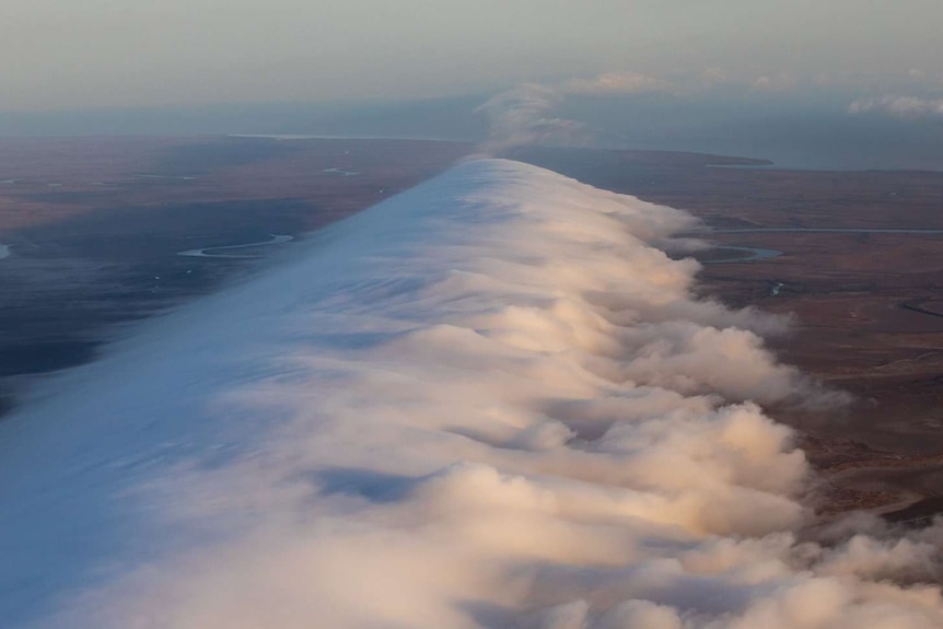 A large white cloud with land and sea below.