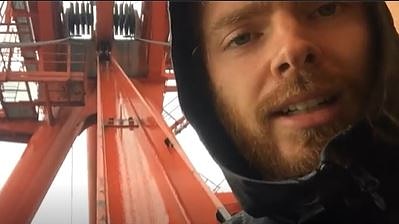 a man looking at a camera after having climbed a crane