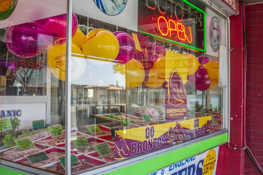 The entrance to the butcher shop is littered with maroon and yellow balloons for the grand final.