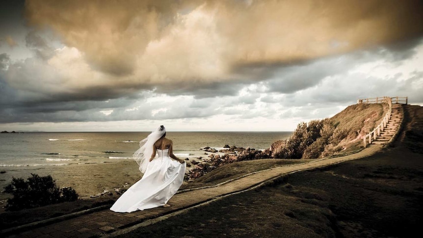 Bride runs along footpath at Byron Bay