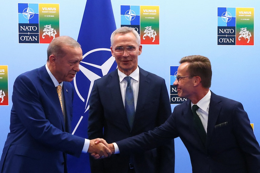 Erdogan and Kristersson shake hands, Stoltenberg stands between them and looks at the camera