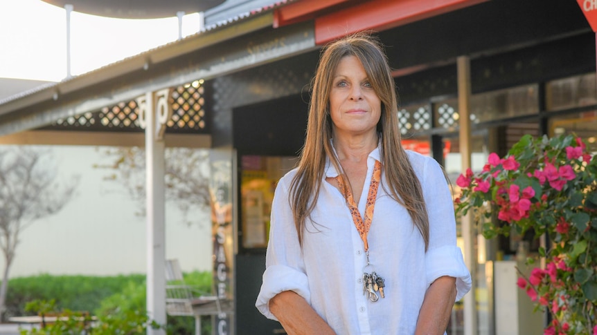 A woman stands outside her newsagency in Carnarvon.