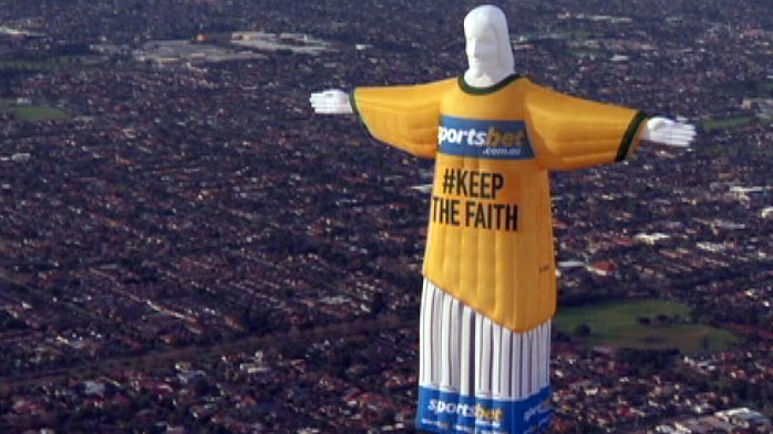 Hot air balloon depicting Jesus with a sportsbet logo flying over Melbourne's suburbs.