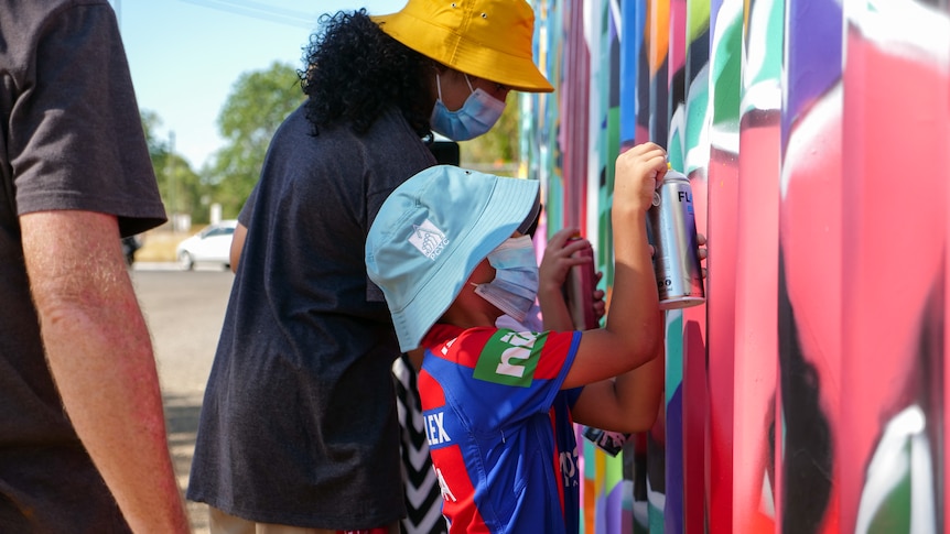 Young people create spray paint art on a shipping container.