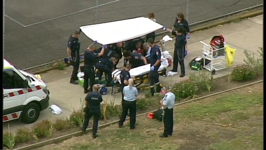 Paramedics work on a man in an outside area of a prison.
