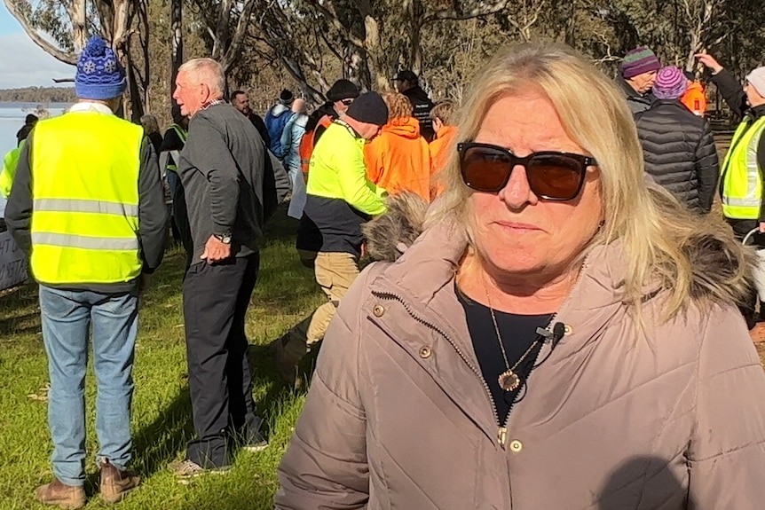 woman in sunglasses looking concerned with group of people behind her 