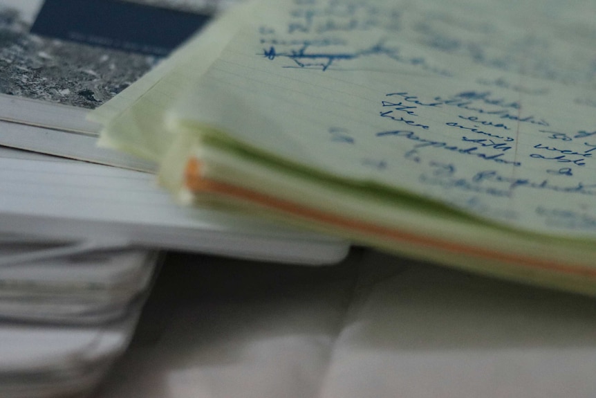 A pile of notebooks with blue pen writing