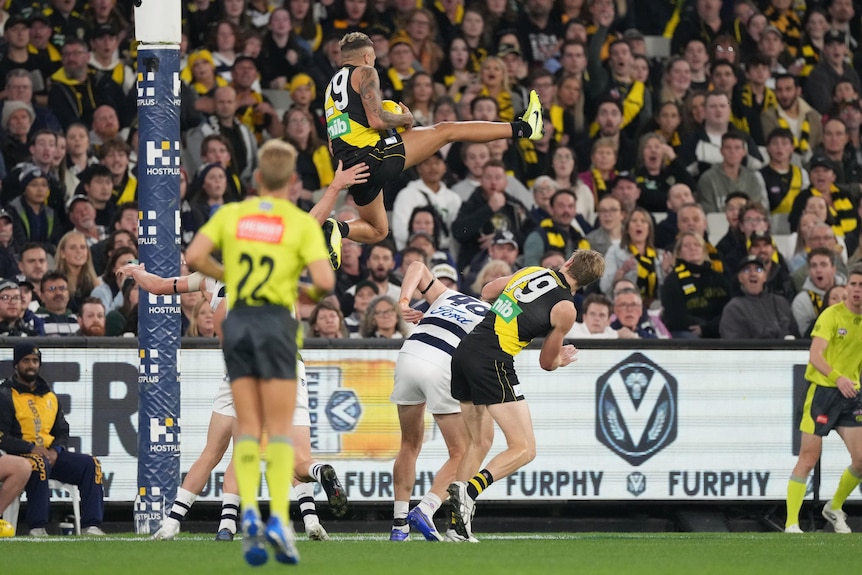 Shai Bolton vole au-dessus d'un groupe de joueurs, donnant un coup de pied à la jambe droite alors qu'il termine une marque spectaculaire