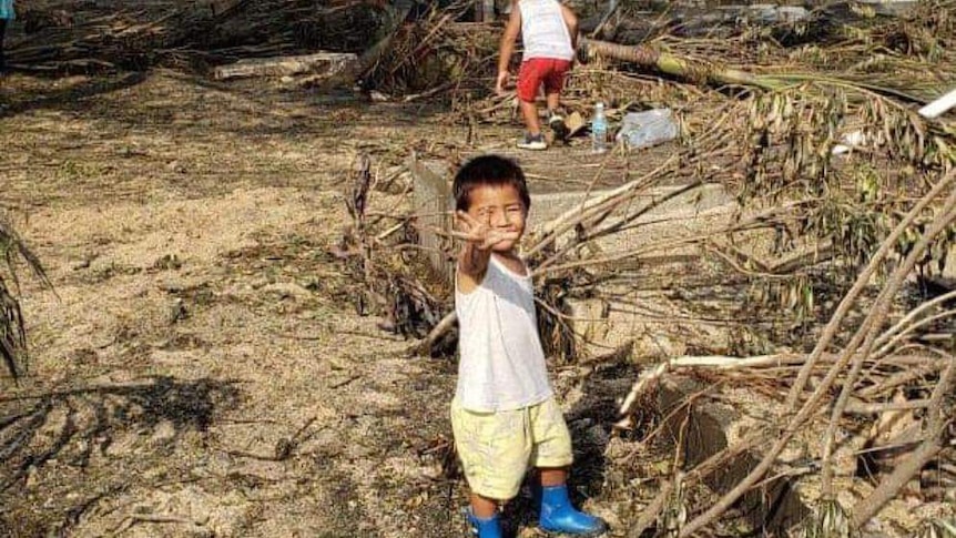 A Tongan boy stands amongst destruction in wake of eruption