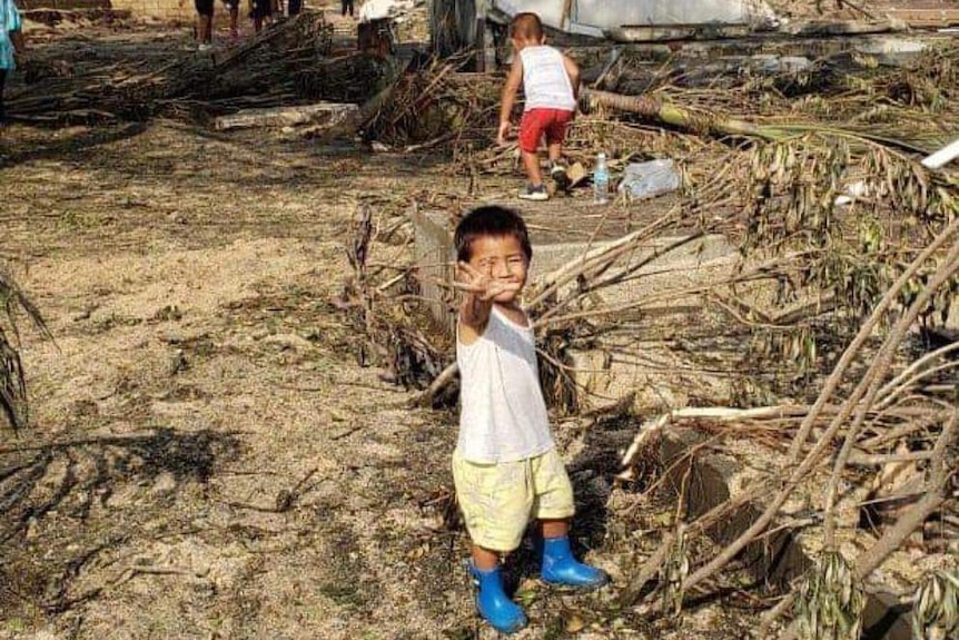 A Tongan boy stands amongst destruction in wake of eruption