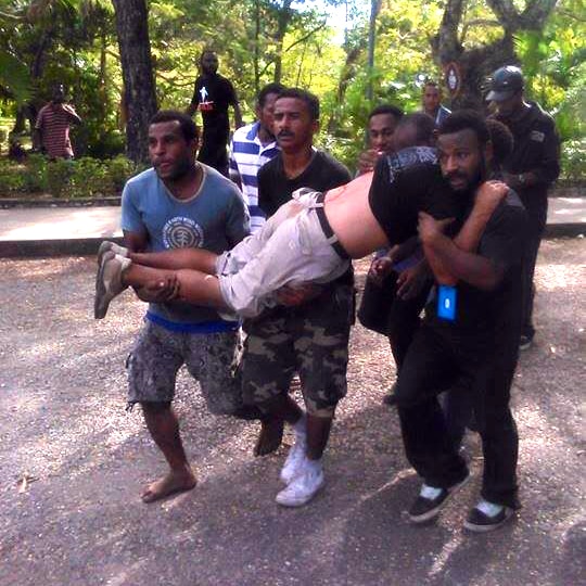 Protesters carry a fellow protester who was shot by police.