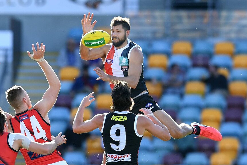 Paddy Ryder leaps towards a yellow ball and looks to catch it with one hand above the ball