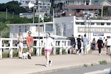 A wide shot of people walking or standing near a beach