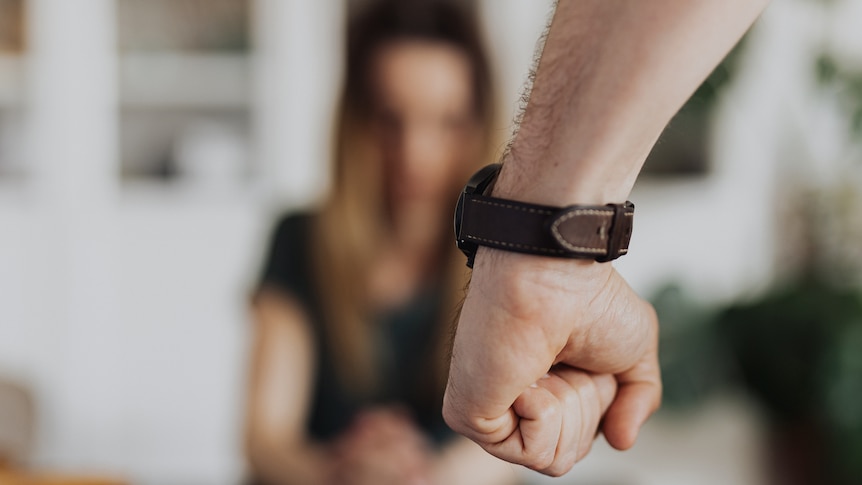 A man's clenched fist in front of a blurred woman's face