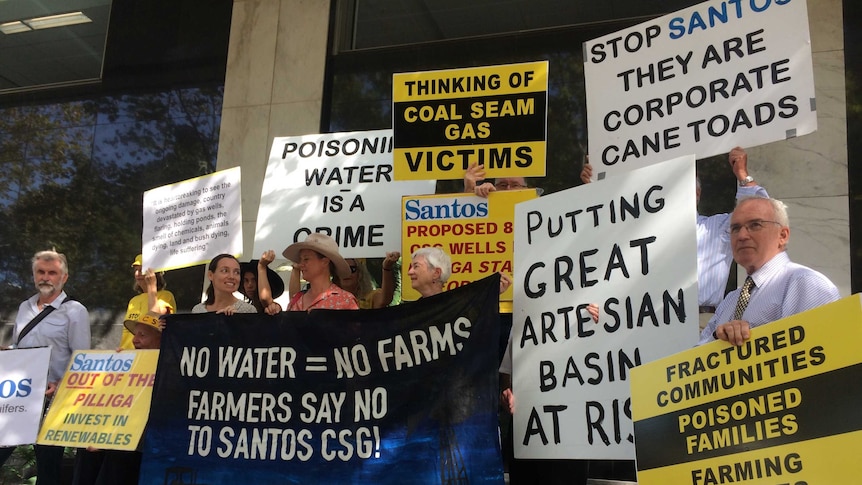 People hold signs saying 'Poisoning water is a crime'.