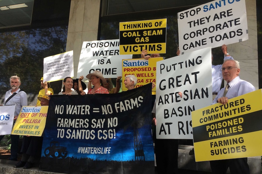 People hold signs saying 'Poisoning water is a crime'.