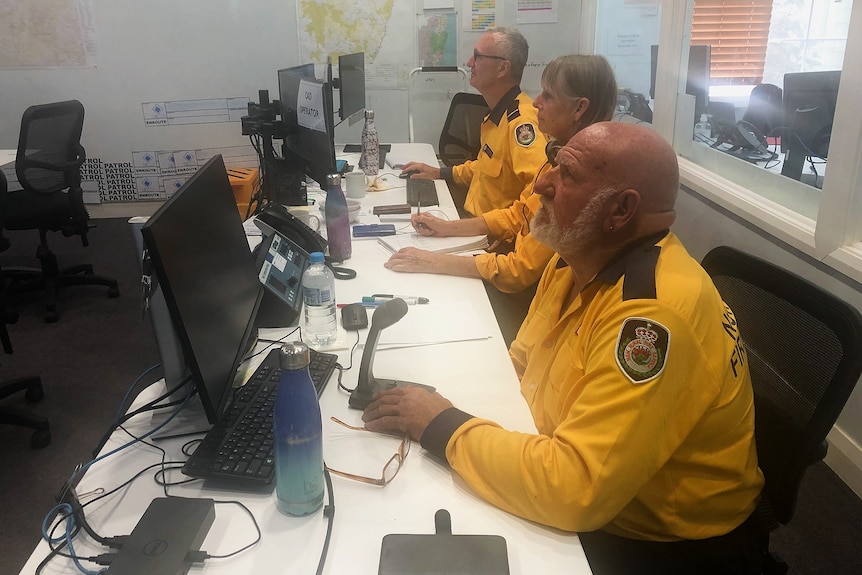 RFS crew in yellow shirts at computer screens on a desk in a row looking up