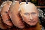 Three flat face masks wrapped in plastic are hung from a string, showing Putin in front, Prigozhin and Lukashenko behind