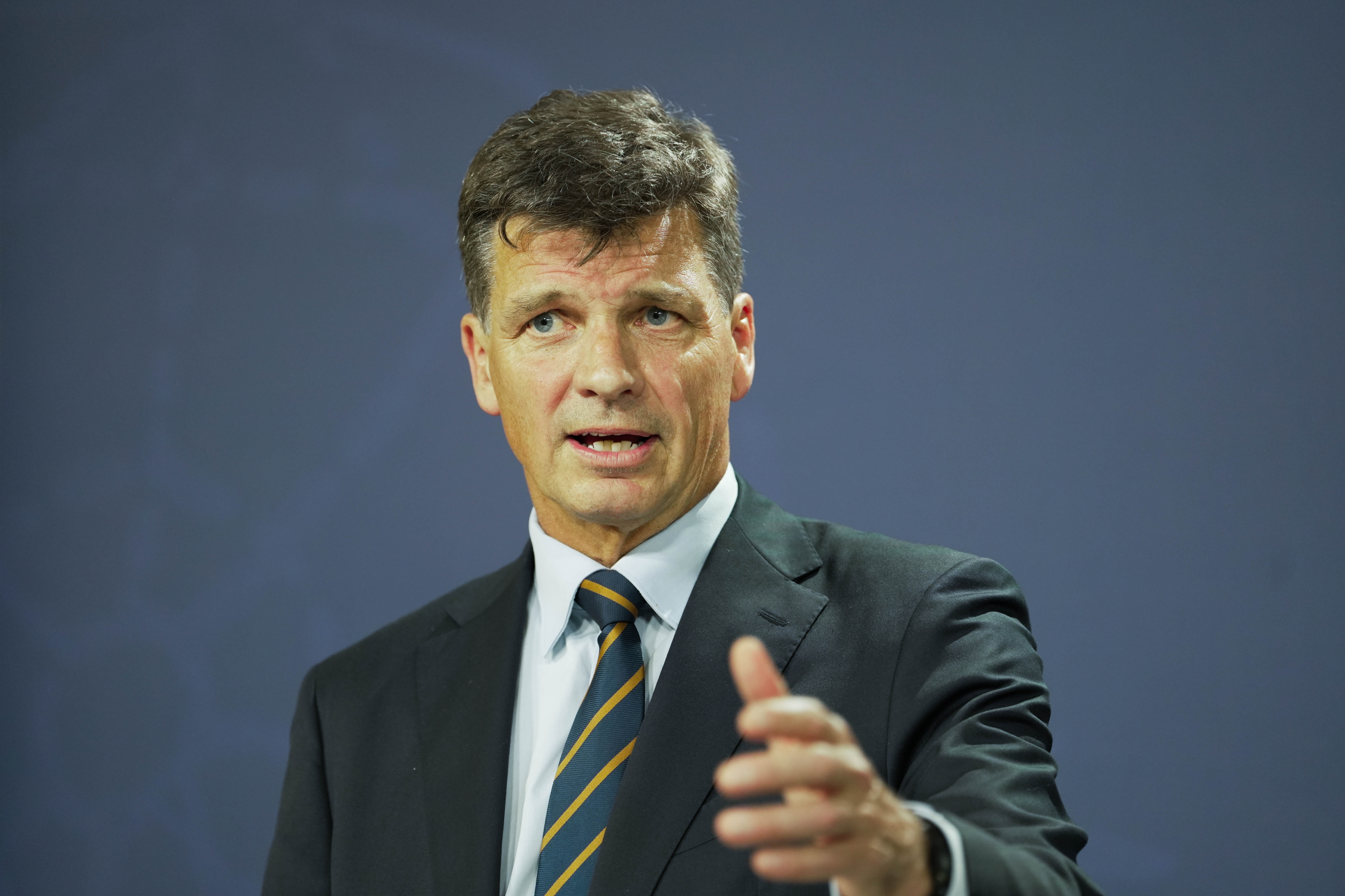 Un hombre mayor con traje pronuncia un discurso apasionado.