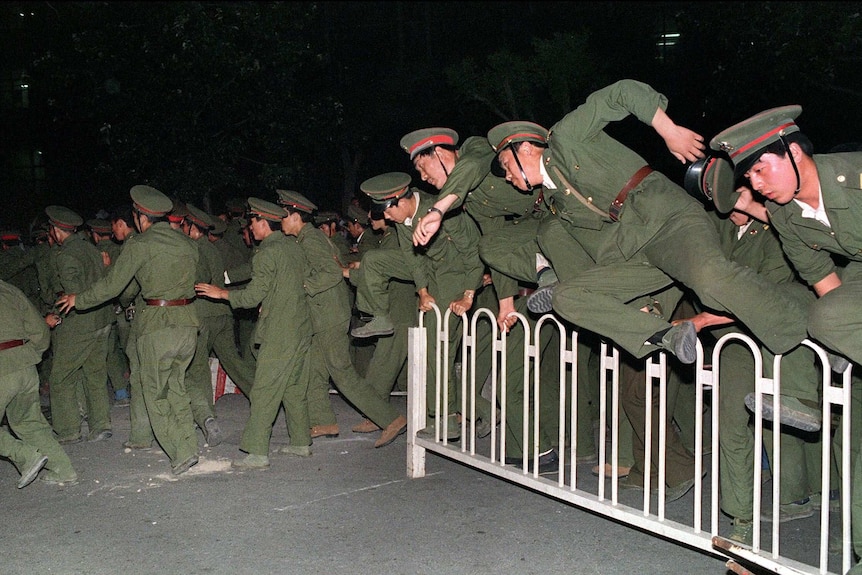 People Liberation Army (PLA) soldiers leap over a barrier on Tiananmen Square.
