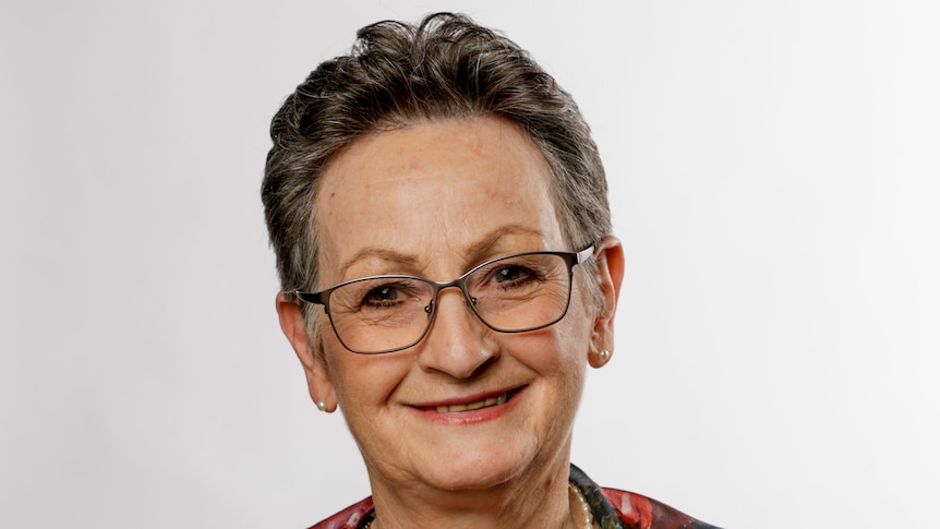 Woman smiles in front of white studio background. 