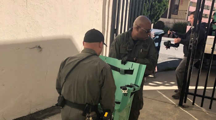Two men carry a lethal injection chair through a gate.