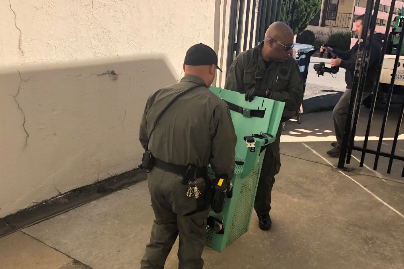 Two men carry a lethal injection chair through a gate.