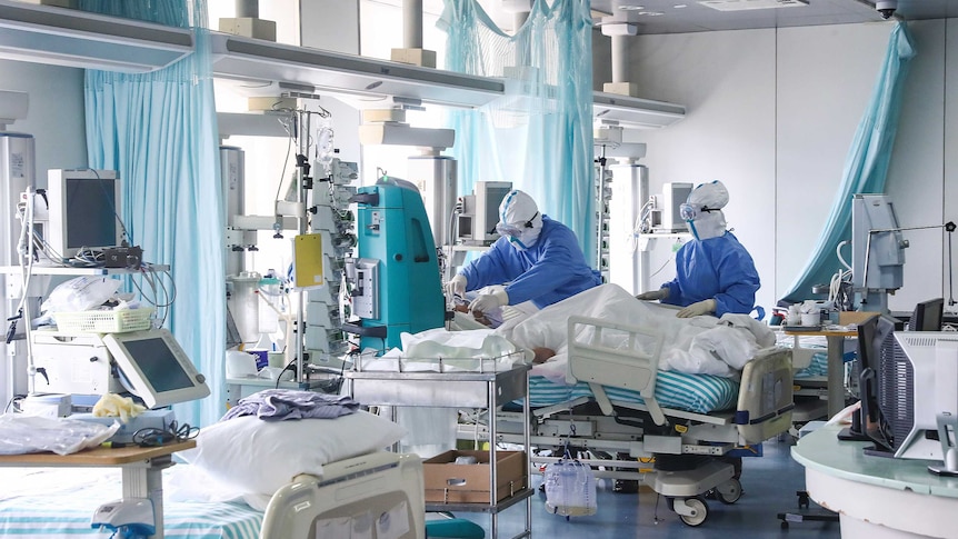 A patient in bed surrounded by doctors.