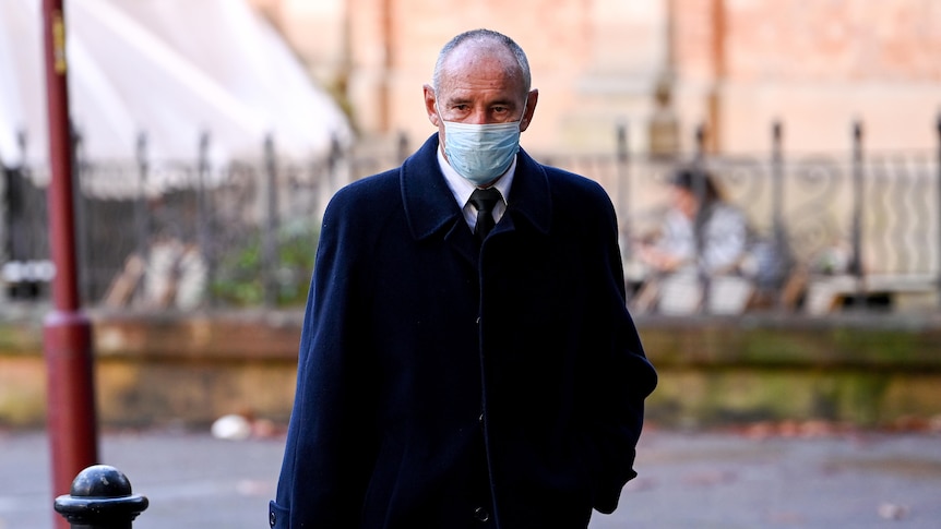 A masked man in a suit and heavy winter coat