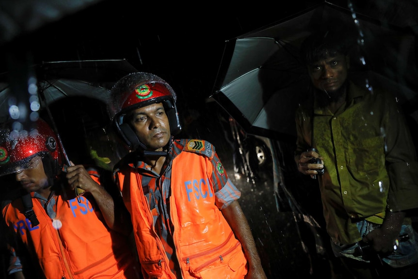 A man wearing a helmet and bright orange jacket looks upset.