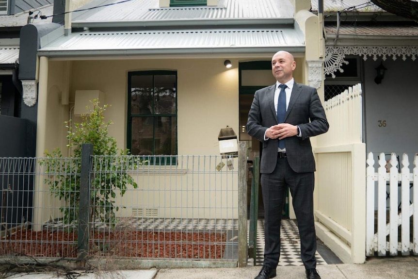 A man poses outside of a house