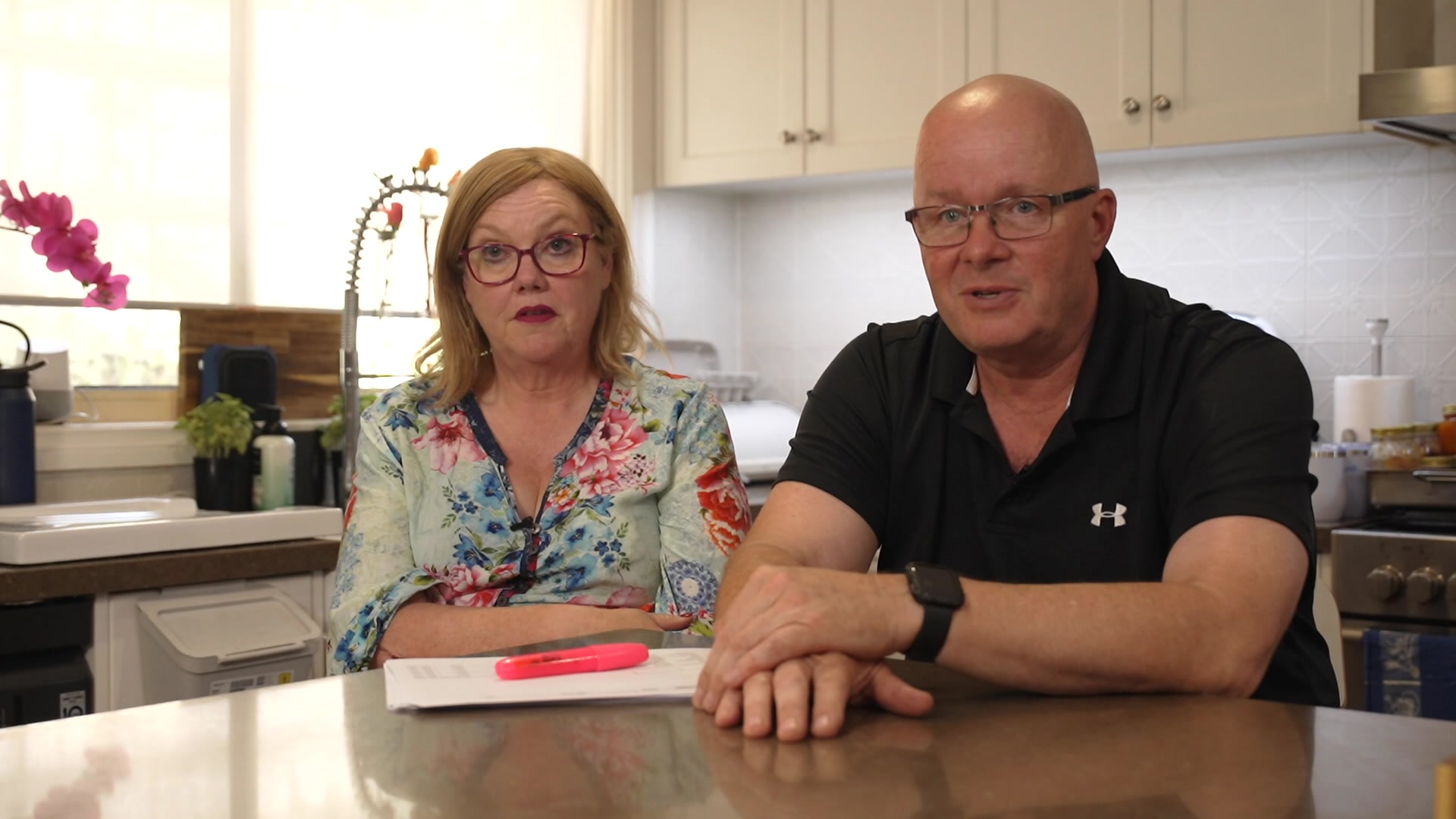 Женщина и мужчина сидят в помещении и улыбаются.