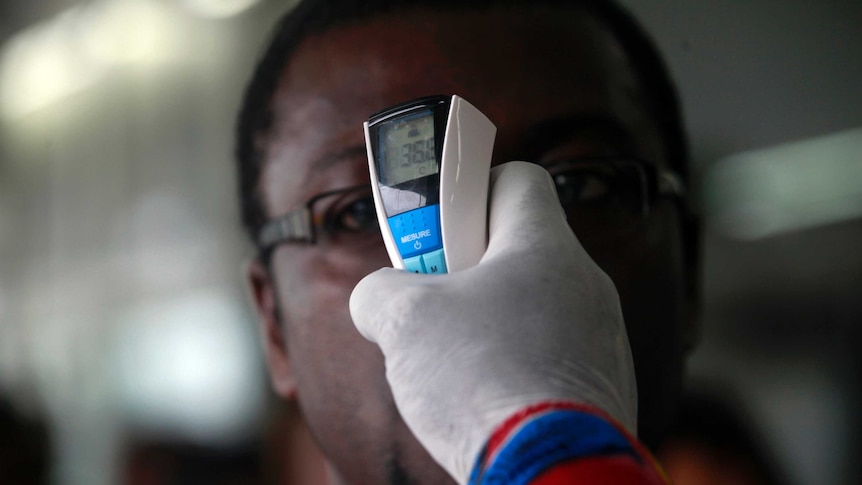 Airport staff take passenger temperature at African airport during Ebola scare
