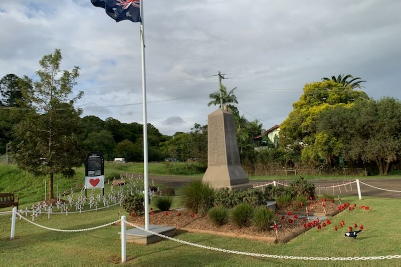A stone memorial surrounded by fake poppies and an Australian flag.