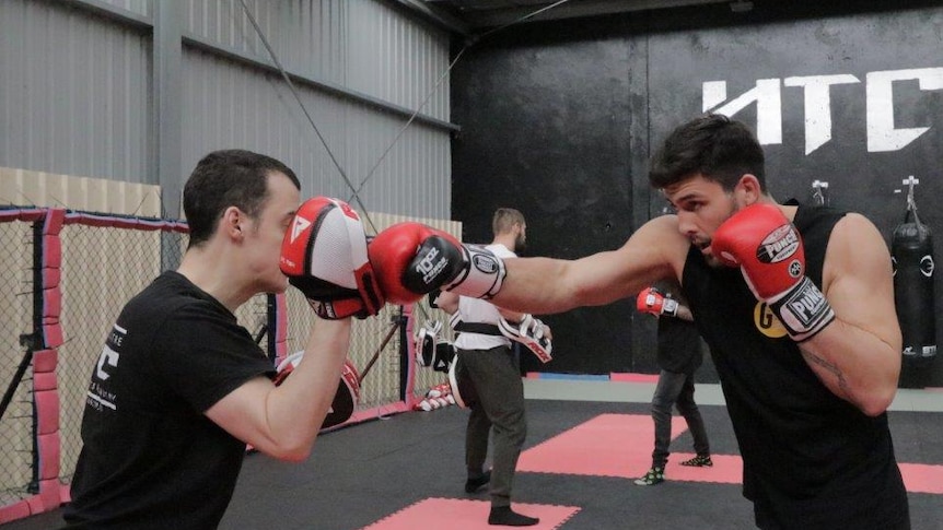 Two mixed martial arts fighters training in a gymnasium