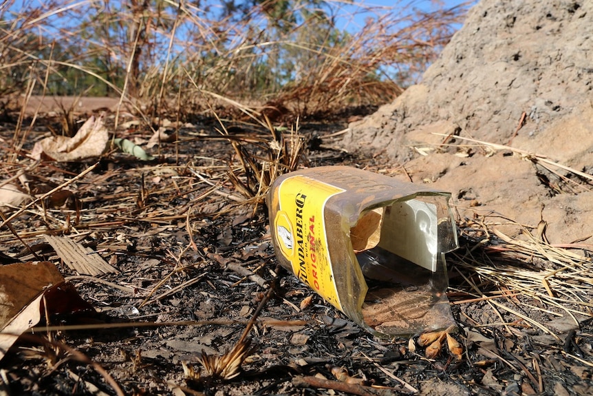 A broken bottle of rum lies in the dirt