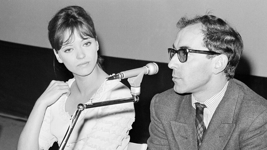 French actress Anna Karina and Jean Luc Godard are seated with a microphone in front of them