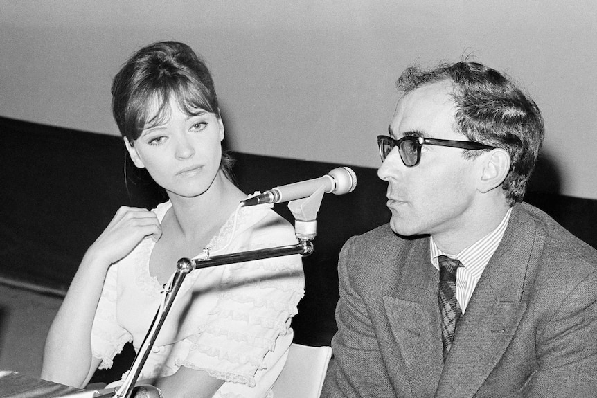 French actress Anna Karina and Jean Luc Godard are seated with a microphone in front of them