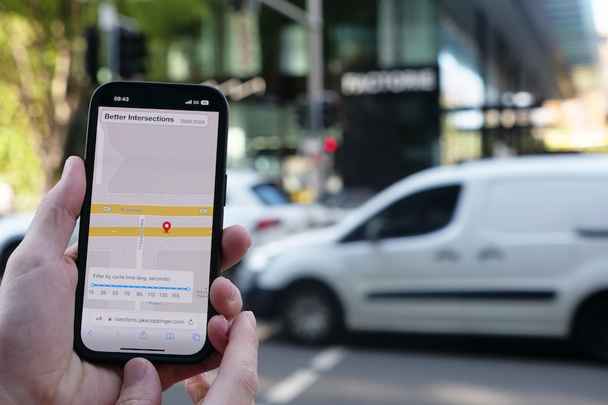 A phone screen in front of a busy intersection