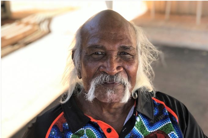 Close up shot of face of indigenous man with straggling white hair looking into the camera