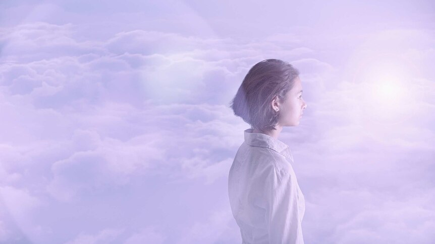 side profile of young woman wearing white amongst the clouds, gazing into the distance