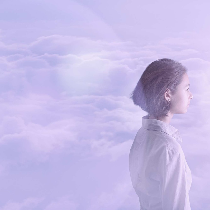 side profile of young woman wearing white amongst the clouds, gazing into the distance