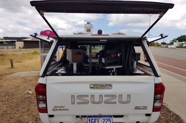 A car with a speed camera in the back, parked on the side of a WA road.