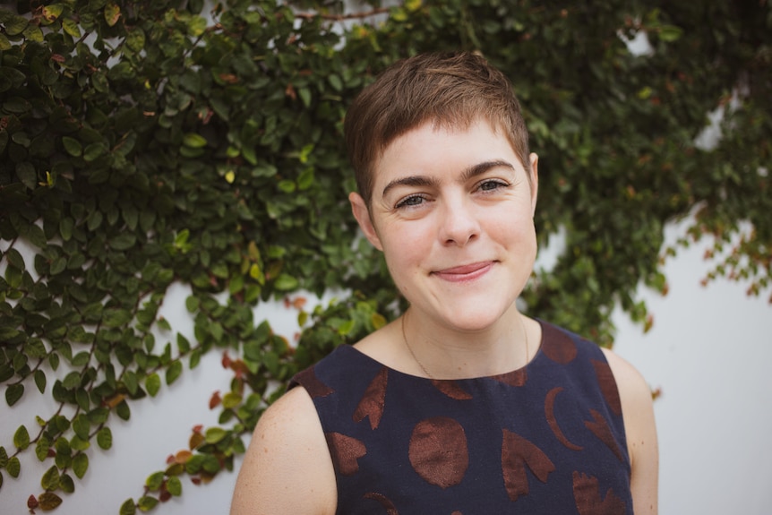 A profile picture of Dr Caitlin McGrane from Deakin University. She is standing in front of a vine-covered wall.